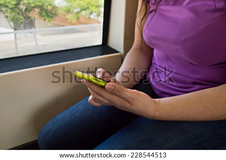 Hand holding mobile smart phone while traveling by train