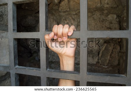 close up of hand of a prisoner grabbed the bars of the prison