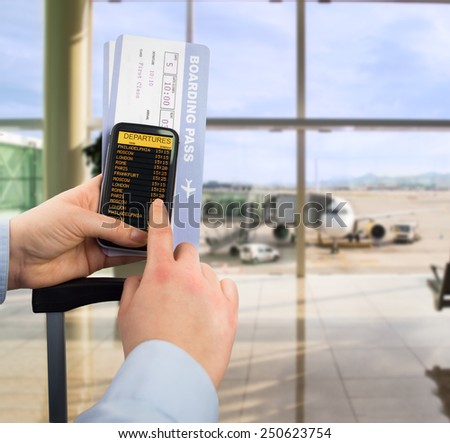 Hand holding mobile smart phone with connect wifi on the airport and see departures board