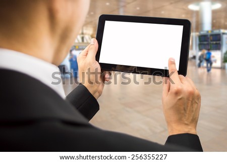 Businessman surfing of a digital tablet at the departure gate of an airport