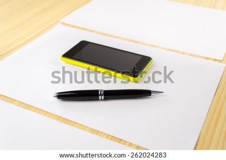smartphone and pen over papers at the office
