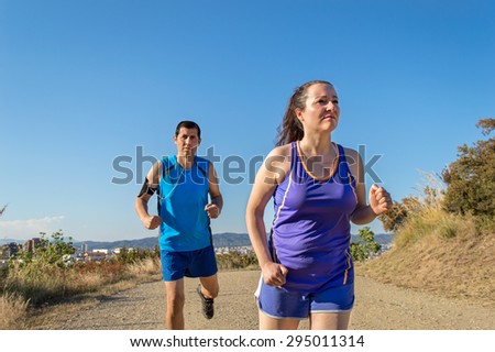 couple of joggers training. woman and man training on park trail outside. man and woman sprinting in the race.