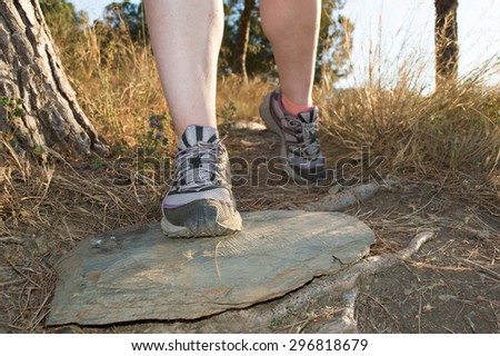 front view of closeup of feet of sportswoman walking along the path in the mountain