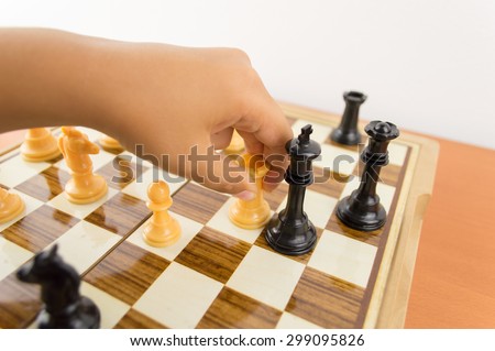 hand of a kid playing chess moving the rook to kill the king - making the checkmate