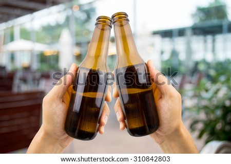 hands raised toasting with beer at the terrace bar in summer time
