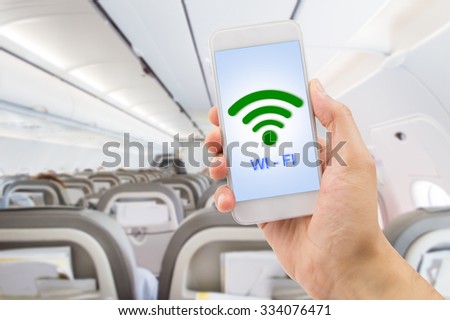 hand holding the smartphone with signal wifi at the indoor of the plane near the aisle