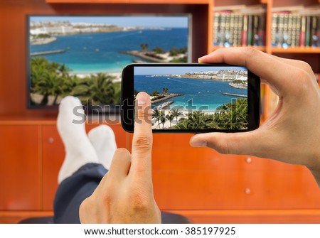 relaxed man with smartphone connected to a tv and envisioning photos in networking