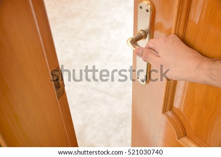detail of hand opening the wooden door