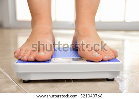 legs of a young woman measuring her weight on a bathroom scale