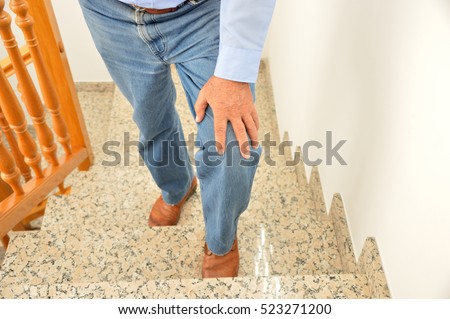 Cropped shot of a senior man going up the stairs at home and touching his knee by the pain of arthritis