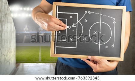 hand of a football coach drawing a tactics of soccer game with white chalk on blackboard at arena tunnel