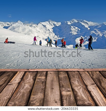 Wooden deck with view on a ski slope and white mountains