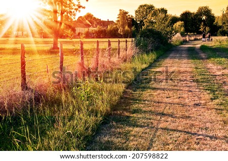Countryside landscape with a field and a village in the sunset