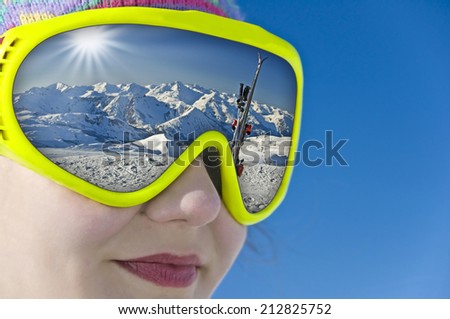 Close up of a girl with a ski mask reflection a snowy mountain landscape and the ski slope
