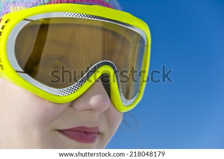 Close up portrait of a smiling girl with ski mask, blue ski background