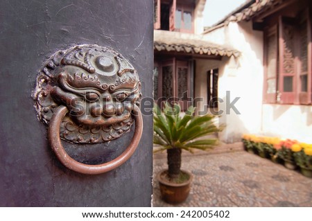 Patio of a traditional chinese house behind a closed door with a lion head knocker