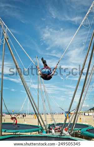 Boy jumping on a trampoline with elastic ropes on a beach