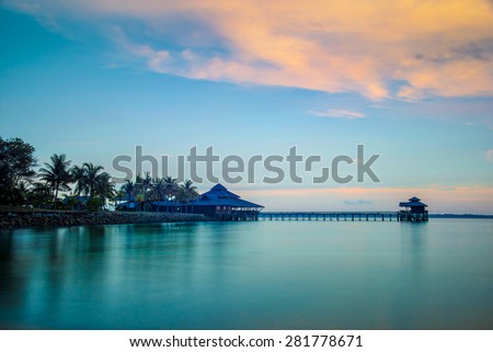 Landscape of water house on stilts, pontoon and palm trees at sunset in Indonesia