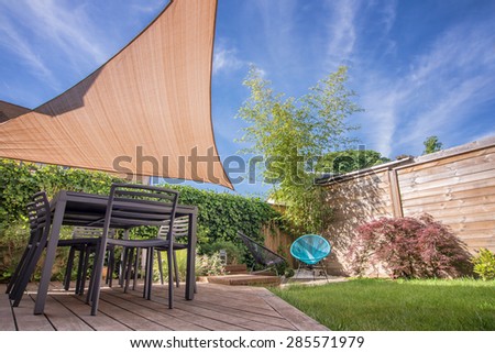 Modern house terrace in summer with table and shade sail