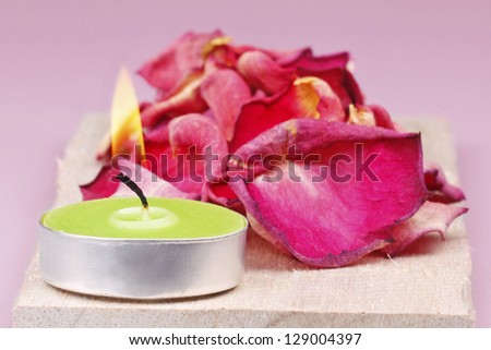 Closeup of one green candle with rose petals