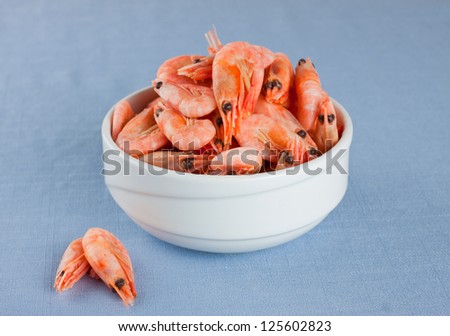 White bowl with boiled shrimps on light blue background