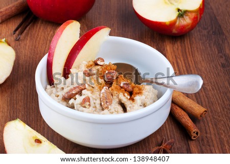 Bowl of apple and cinnamon oatmeal with cut apples on background