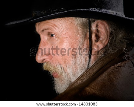 Old cowboy in profile on black background