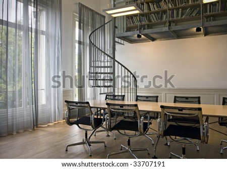 Indoor shot of small office with spiral stairs on background