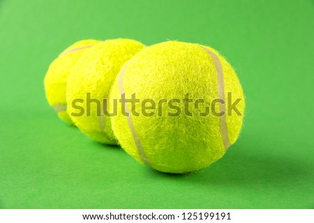 Three yellow tennis balls on green background with selective focus