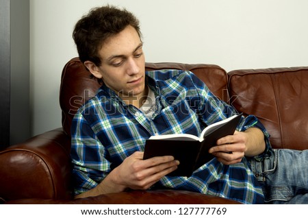 Young man on couch reading book