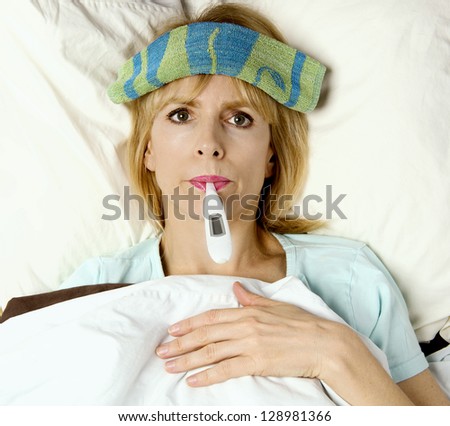 Woman sick in bed or hospital with thermometer in mouth  and washcloth on face