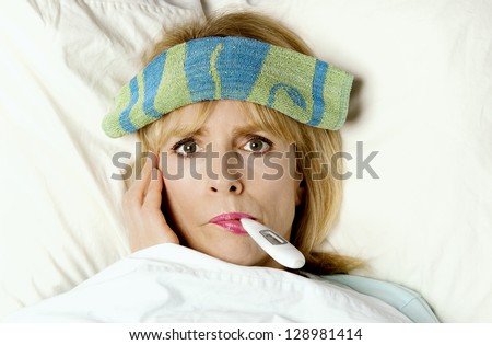 Woman sick in bed or hospital with thermometer in mouth