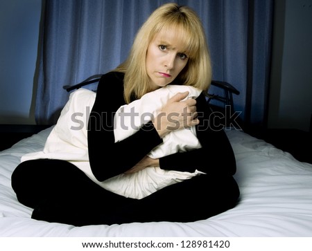 Depressed woman sits on bed
