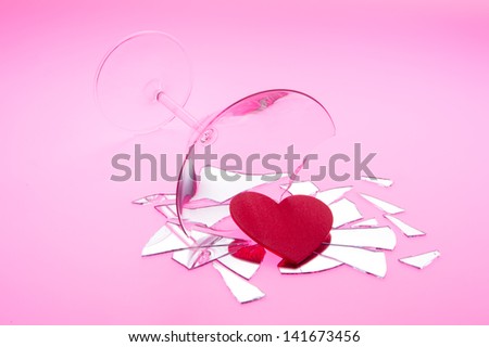 Concept photo of broken relationship with heart spilling out of  broken martini glass shot on light table with red light