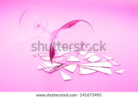 Concept photo of broken relationship with  broken martini glass and shattered mirror shot on light table with red light