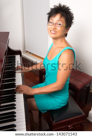 An Asian woman poses at the piano before playing