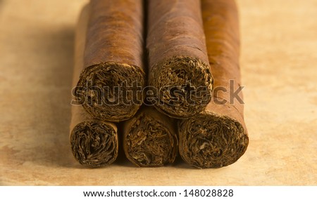 Closeup  of five Cuban cigars rolled and stacked