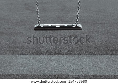 Childhood depression concept with single empty swing in black and white