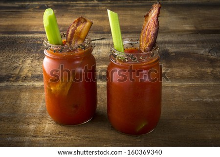 Two Mason Jar Bloody Marys Or Caesars With Bacon On Wood Background
