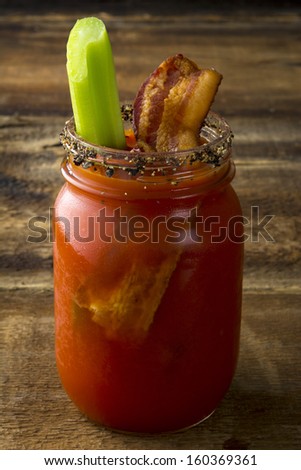 Two mason jar Bloody Mary or Caesar  with  bacon  on wood background
