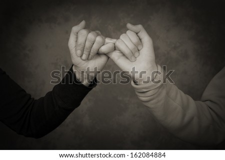 Concept photo for mother and daughter relationship with hands and fingers linked in this desaturated image
