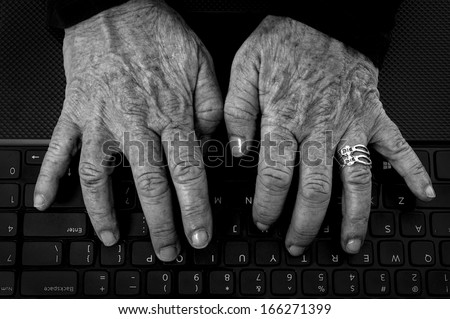 Closeup of  old  woman\'s hands with arthritis on computer keyboard in black and white