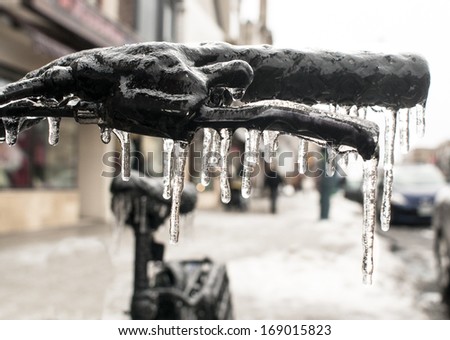 Bicycle handlebars are encased in ice with icicles after ice storm in closeup photo