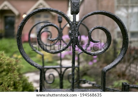 Ornate antique wrought iron detail on fence in front of house