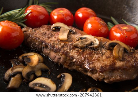 Series: Grilling Strip Loin Steak in Cast Iron Frying Pan: Steak  is cooked and shown with grilled tomatoes and mushrooms