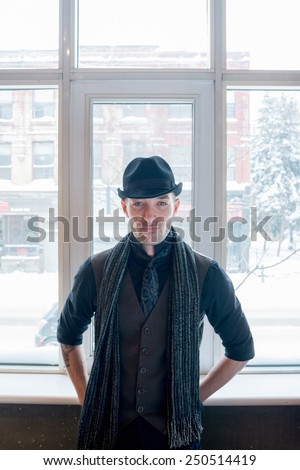 Portrait of a stylish man with tie and scarf posed against a window