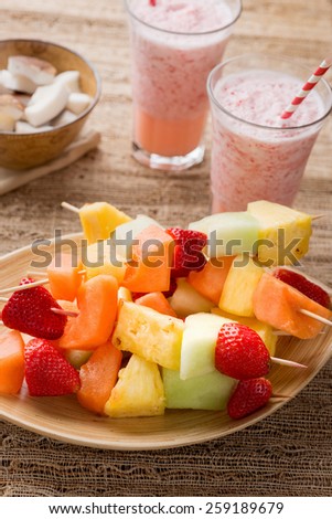 Fruit kabobs - fruit on skewers - on tray with strawberry smoothies