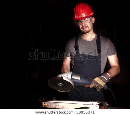 manual worker with grinder and dark background