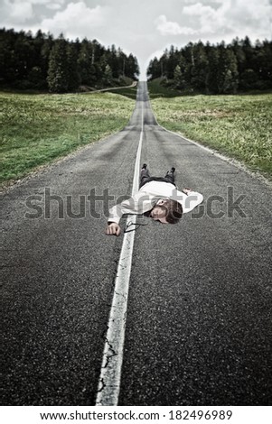 businessman lying down on long road