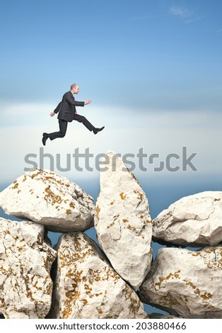 businessman jump over huge rock